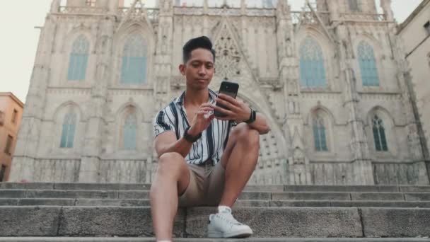 Jovem Turista Passos Usa Telefone Celular Enquanto Sentado Marcos Fundo — Vídeo de Stock