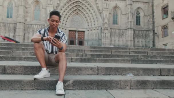 Junger Mann Tourist Auf Stufen Benutzt Handy Während Auf Wahrzeichen — Stockvideo