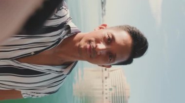 Rıhtımda durup cep telefonuyla selfie çeken genç adamın yakın çekimi.