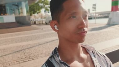 Rıhtımdaki bankta oturan genç adamın yakın çekimi, müzik dinliyor. Arkaplan