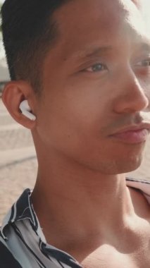 Rıhtımdaki bankta oturan ve müzik dinleyen genç bir adamın yakın çekim görüntüleri. Arkaplan