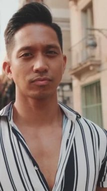 Kollarını kavuşturup kameraya bakan genç bir adam var ya hani? Kamera ileri gidiyor.