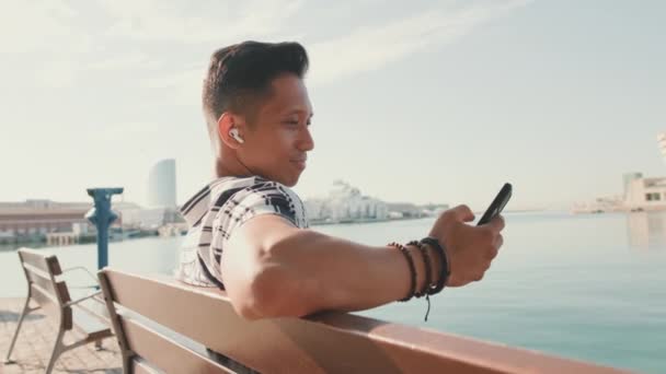 Jeune Homme Touriste Assis Sur Banc Sur Jetée Utilise Téléphone — Video