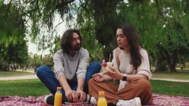 Çift parkta piknikte sağlıklı atıştırmalıkların tadını çıkarıyor.