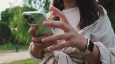 Cep telefonu kullanan genç bir kadının ellerini yakın plan çek.