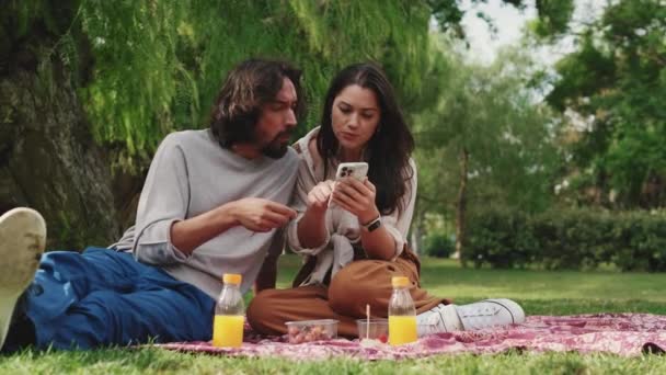 Szerelmes Pár Mobiltelefonnal Piknikezik Parkban — Stock videók
