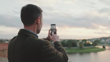 Adam resimli nehir kıyısının videosunu çekiyor. Arka plan