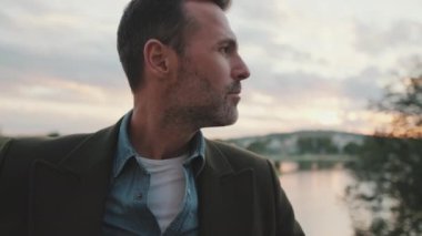 Yakından, adam nehrin arka planında dikilip etrafına bakıyor.