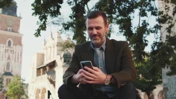 Middelbare Man Aan Het Praten Mobiele Telefoon Oude Stad Achtergrond — Stockvideo