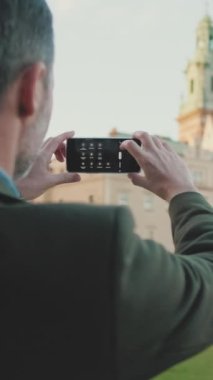 Yakın çekim, eski kentteki cep telefonuyla fotoğraf çeken bir adam. Arka plan