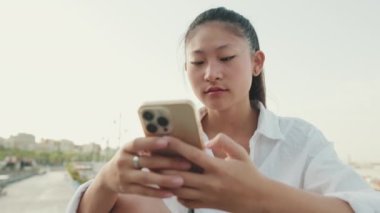 Kapatın, genç bayan limanda otururken cep telefonu kullanıyor.