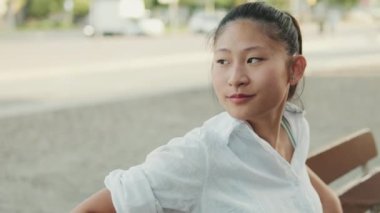 Bankta oturan ve gözlerini kaçıran genç bir kadının yakın çekimi.