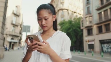 Yolun kenarında dururken cep telefonu kullanan genç bir kadın.