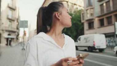 Yolun kenarında dururken cep telefonu kullanan genç bir kadın. Kız etrafına bakıyor.