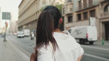 Yolun kenarında dururken cep telefonu kullanan genç bir kadın. Kız etrafına bakıyor.