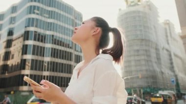 Genç bir kadın dışarıda dikilip akıllı telefonunda harita uygulamasını kullanıyor.