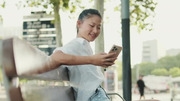 Glimlachende Jonge Vrouw Zitten Bank Met Behulp Van Mobiele Telefoon — Stockvideo