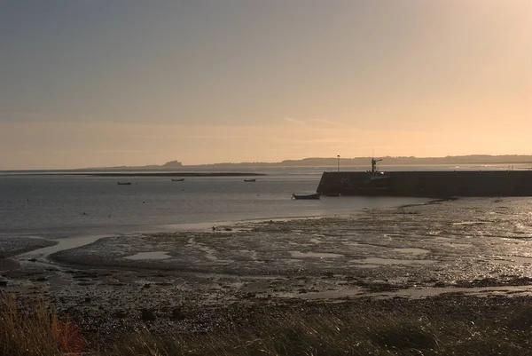 Gün batımında Lindisfarne limanından Bamburgh kalesine manzara — Stok fotoğraf