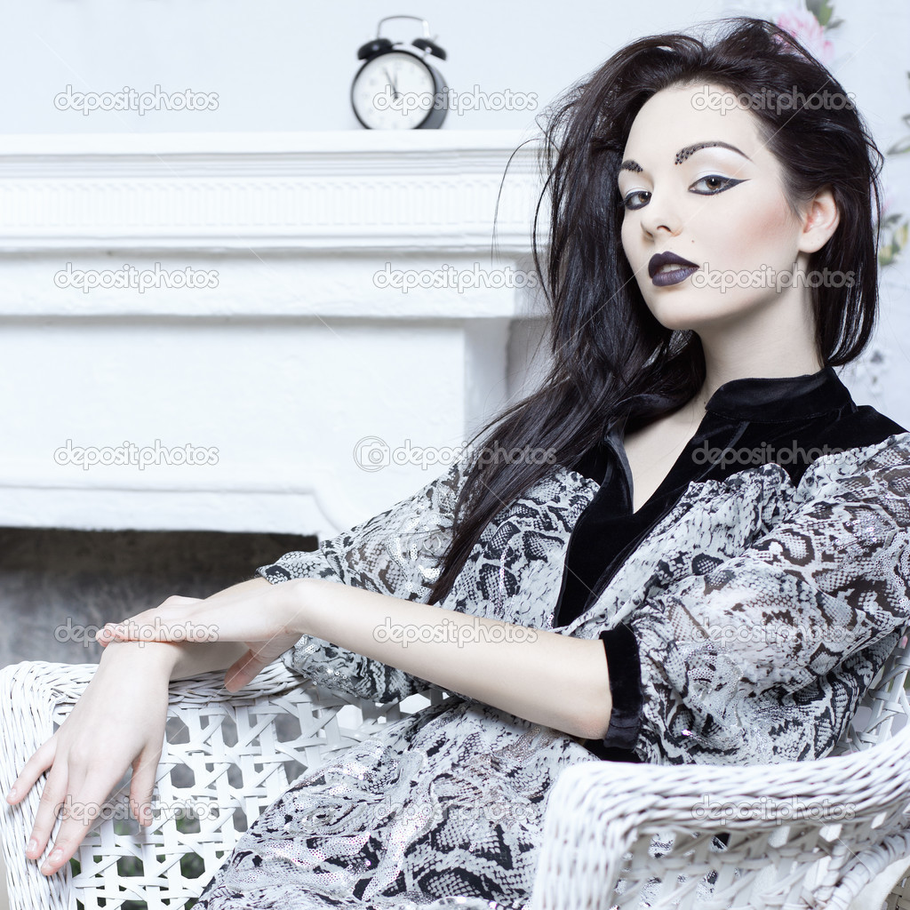 Close-up of beautiful girl sitting in a chair. Bright makeup.