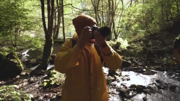Mannelijke toeristische reiziger het nemen van foto 's van stromende berg rivier met camera. — Stockvideo