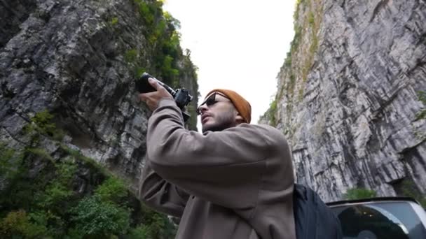 수염을 기른 사진사가 야생 숲의 자연 사진을 카메라로 찍고 있다. — 비디오