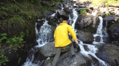 Mountain River şelalesi. Kayaların arasında fotoğraf çeken erkek turist..