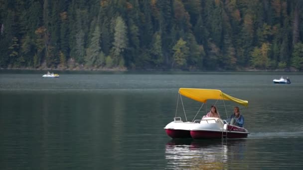 在静止不动的高山湖水中，女旅行者驾驶着旅游船。. — 图库视频影像