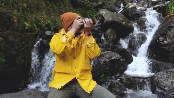 Gebirgswasserfall. Männlicher Touristenfotograf fotografiert zwischen Felsen. — Stockvideo