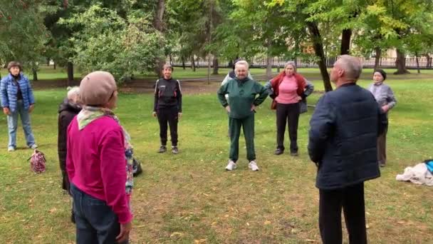 Old people fitness in open air city park. Aged men and women sports exercise. — Stock Video