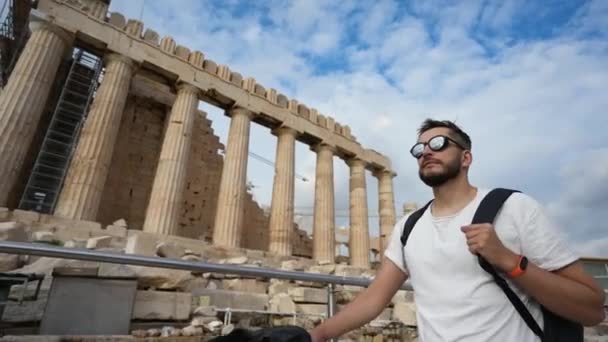 Ταξιδιώτης με γυαλιά περπατά στην Ακρόπολη και κοιτάζει γύρω του παλιά Ελληνικά αξιοθέατα. — Αρχείο Βίντεο