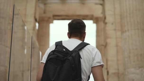 Touriste masculin regarde autour parmi les piliers de l'ancien temple Acropole à Athènes. — Video