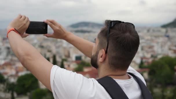 Άνδρας μεταξύ τουριστών φωτογραφίζει με τηλέφωνο την Ακρόπολη στο λόφο της Αθήνας — Αρχείο Βίντεο