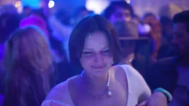 Гарна брюнетка біла кавказька дівчина танцює серед натовпу людей, які кидаються в клубки.. — стокове відео