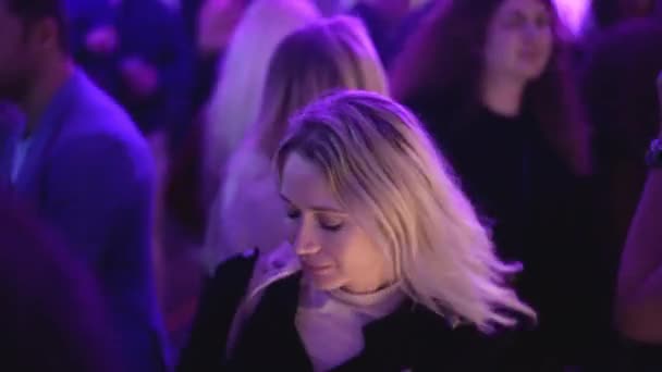 Blonde European girl dances in night club in crowd of party people. Cute female — Stock Video
