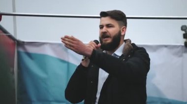Sahnede mikrofonlu kızgın erkek konuşmacı insanlara önemli bir mesaj iletiyor.