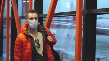 Maskeli gezginler havaalanı terminali lobisinde ayrılıyor ya da uçağa biniyor..