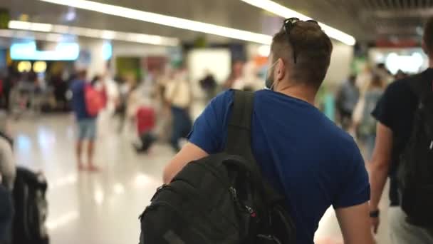 Zamaskowani podróżnicy opuszczający lub wsiadający do samolotu w holu terminalu lotniska. — Wideo stockowe