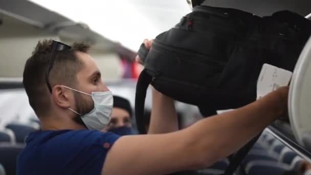 Пассажиры грузят сумки, чемоданы на полки. Посадка на самолет. — стоковое видео