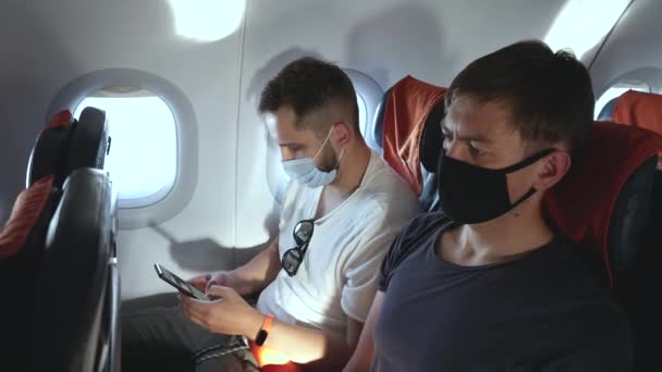 Pasajero enmascarado usa teléfono para enviar mensajes de texto en el vuelo del avión, restricciones covid. — Vídeos de Stock