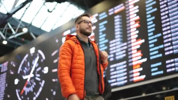 Guy v brýlích s batohem procházky letu příletové palubě na letišti terminálu. — Stock video