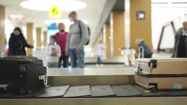 Turistas y viajeros esperan la llegada de bolsos facturados, maletas en la terminal. — Vídeos de Stock