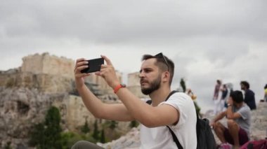 Atina tepesindeki Yunan Akropolünün telefonuyla fotoğraf çeken turistler arasında erkek