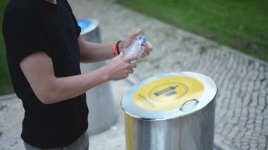 Adam tek plastik şişeyi ayrı çöp kutusuna atıyor. Şehir atığı sıralama.