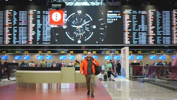 Чоловік з рюкзаком, що йде в терміналі аеропорту під бортом . — стокове відео