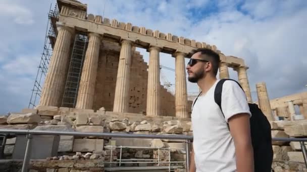 Muž turista tráví čas na procházky mezi pilíři starověké Akropole v Aténách — Stock video