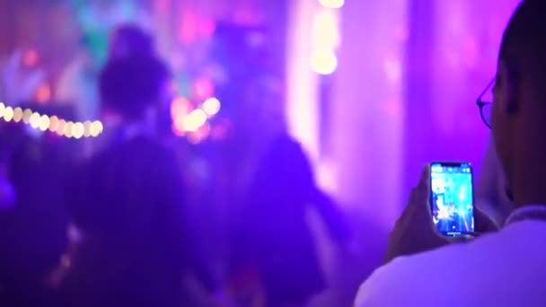 Schwarzer Mann filmt mit Smartphone tanzende Menschen in Nachtklub. Platz für Anzeigentext. — Stockvideo