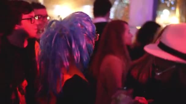 Cool bebaarde man met bril en blauwe pruik dansen in menigte van feestgangers. — Stockvideo