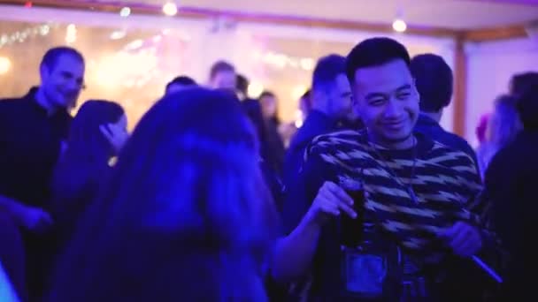 Asiatischer Mestizomann tanzt in Menge clubender Menschen und hält Getränk im Glas. — Stockvideo