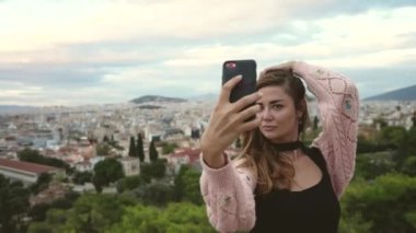 Turist kadın, antik Yunan Akropolis Tepesi arka planında telefon özçekimi çekiyor.