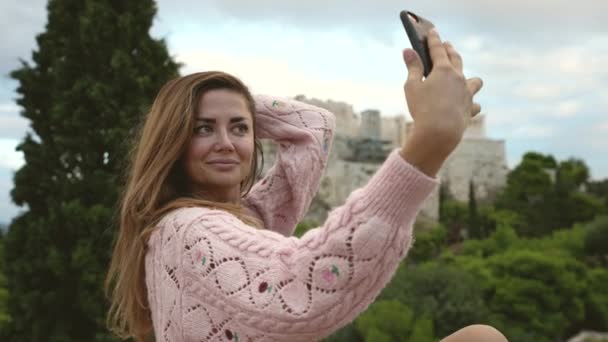 Female tourist takes selfies on Acropolis hill in Athens. View of ancient ruins. — Stock Video